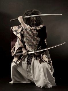 a woman dressed in traditional japanese clothing holding two swords