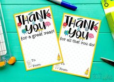 two thank you note cards sitting on top of a table next to pens and pencils