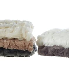 three blankets are stacked on top of each other in different colors and sizes, one is white, the other brown