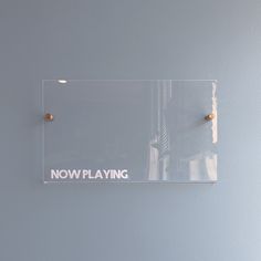 there is a glass sign that says now playing on the wall next to a light switch