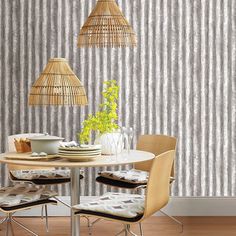 a dining room table with chairs and a vase on top of it next to a wallpapered wall