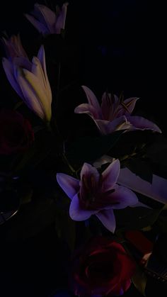 some flowers are sitting in a vase on the table and one is lit up with purple light