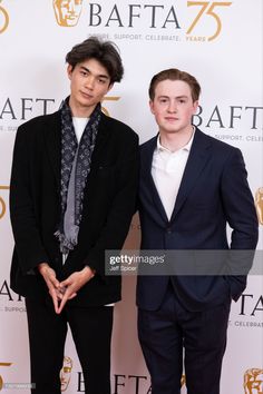 two young men standing next to each other on the red carpet at an awards event