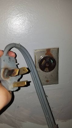 a person is holding an electrical wire and plugged in to a light switch box