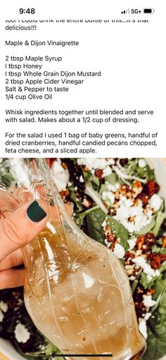 a person holding up a glass pitcher filled with liquid next to a bowl of salad