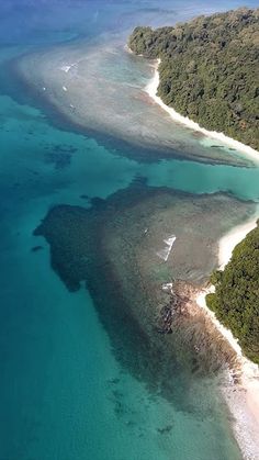 an aerial view of the ocean and landforms in the tropical island area, with trees on both sides