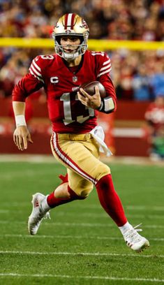 a football player running with the ball in his hand and people watching from the stands