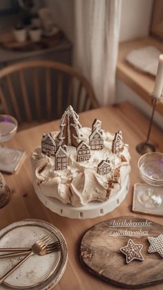 a table topped with a cake covered in icing and gingerbread houses on top of it