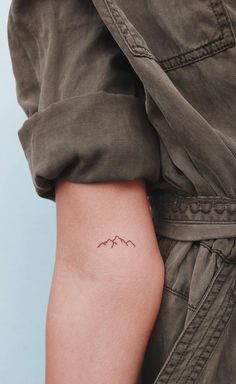 a woman's arm with a small mountain tattoo on the left side of her right arm