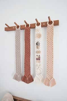 three scarves are hanging on a wall with wooden pegs in the middle and one has tassels attached to it