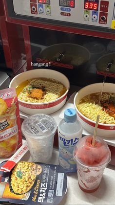 three bowls of food sitting on top of a counter next to drinks and water bottles