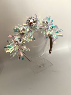 a headband made out of glass beads and other colorful objects on a clear stand