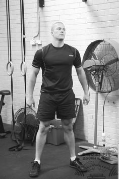 a man standing next to a fan in a room