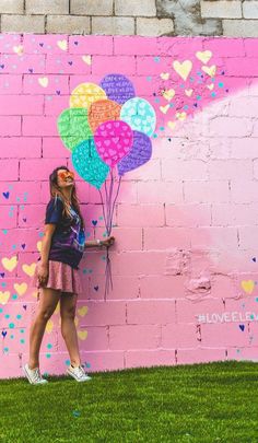 a woman standing in front of a wall with balloons painted on it