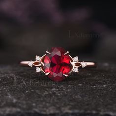 a close up view of a ring with a red stone in the middle and white diamonds around it