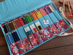 an assortment of colored pencils and crayons in a blue case on a wooden table