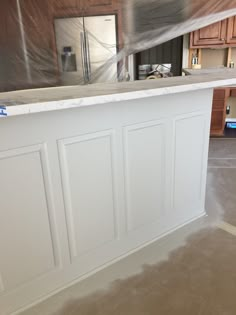 an unfinished kitchen with white cabinets and marble counter tops