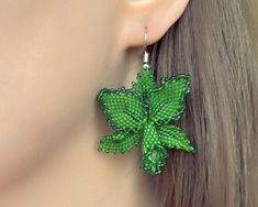 a pair of earrings with green leaves on them