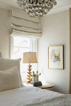 a bedroom with a chandelier hanging from the ceiling next to a white bed