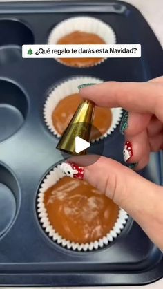 a person holding a cupcake in front of some muffin tins with chocolate frosting on them