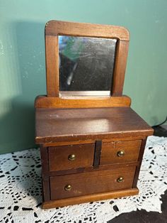 an old wooden dresser with a mirror on it's top and drawers below the drawer