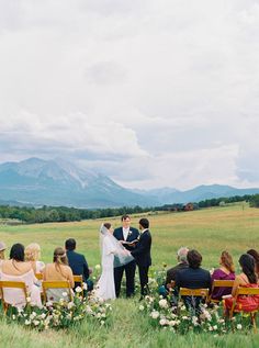 a bride and groom standing at the end of their wedding ceremony with mountains in the background