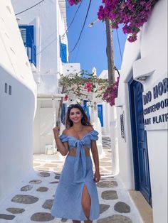 a woman in a blue dress is walking down the street