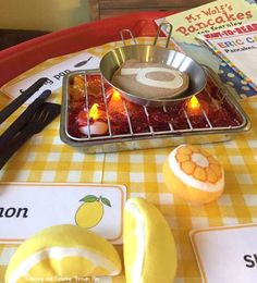 a table topped with food and utensils on top of a yellow checkered table cloth