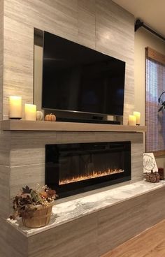 a living room with a flat screen tv on the wall and candles in front of it