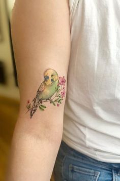 a small bird on the arm with flowers and leaves around its neck, sitting on a woman's left arm