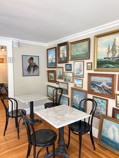 there are many paintings on the wall in this dining room with black chairs and tables