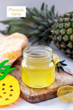 pineapple syrup in a glass jar next to sliced pineapples on a cutting board