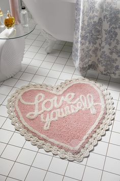 a pink heart shaped rug with the words love you on it in front of a bathtub