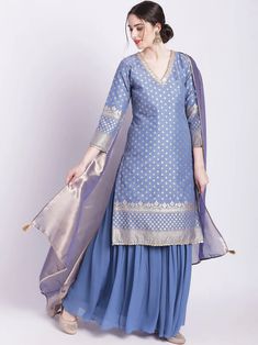 This timeless ensemble showcases the classic beauty of blue banarasi chanderi with luxurious zari work. Included is a kurta, an elegant georgette sharara, and a two tone organza dupatta, perfect to add a sophisticated touch to any occasion. No. of pieces - 3 piece set. Color - Blue. Fabric - Banarsi Chanderi, Georgette and Organza. Kurta Length - 40 inches. Washing Instructions - Dry Clean. Indian Designer Suits Party Wear, Banarasi Suit Designs, Traditional Dresses Indian, Suit Designs Indian Style, Organza Kurta, Kurta And Sharara, Georgette Sharara, Indian Sari Dress, Indian Designer Suits