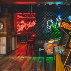 a room with neon lights and video games on the walls, along with stools