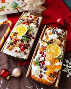 two trays filled with fruit and nuts on top of a red table cloth next to christmas decorations