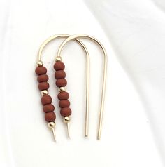 Adorn your ears with a touch of luxe! Our Cheval - Gold & Burnt Sienna Beads earrings are as classy and sophisticated as they come! Featuring a shimmering gold threader, they're decorated with deep, burnt sienna colored beads for a modern yet timeless look. 14k Gold Filled Measure approximately 1.25 Inches Quality Miyuki Seed Beads Sent in a Ribboned Gift Box Handmade in Montana 14k Gold-filled Beaded Drop Earrings, Gold Tiny Beads Drop Earrings, Gold Drop Earrings With Tiny Beads, Adjustable Beaded Earrings With Dangling Beads For Everyday, Elegant Adjustable Brass Beaded Earrings, Elegant Gold Earrings With Tiny Beads, 14k Gold-filled Tiny Beaded Earrings, Adjustable Hoop Earrings With Gold Beads As Gift, Adjustable Gold Beads Hoop Earrings As Gift