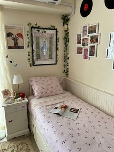 a bed with pink sheets and pictures on the wall next to a dresser in a bedroom