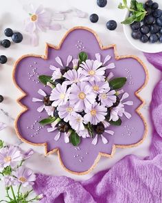 purple flowers and blueberries are arranged in the shape of a flower on a plate