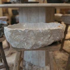 a stone bowl sitting on top of a wooden stool