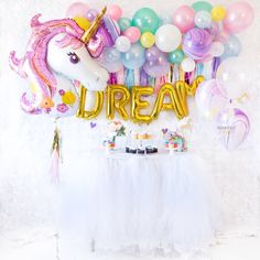 a unicorn themed birthday party with balloons, streamers and desserts on the table