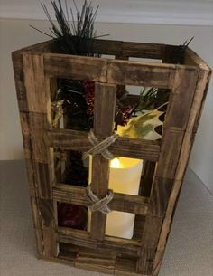 a wooden crate with some plants and candles in the center, tied up to it's sides