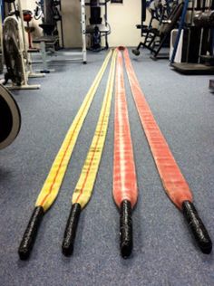 three different colored handles in the middle of a gym floor with other equipment behind them