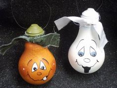 two painted pumpkins sitting next to each other on a black surface with a white ribbon