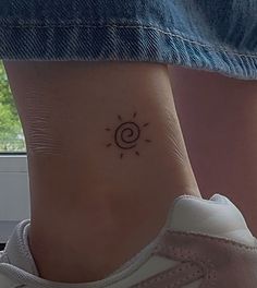 a woman's foot with a small sun tattoo on the side of her ankle