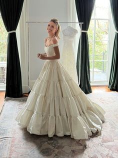 a woman standing in front of a wedding dress