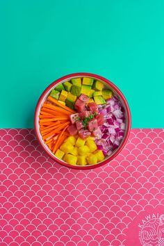 a bowl filled with cut up vegetables on top of a pink tablecloth next to a green wall