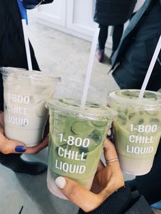 three people holding up two cups with liquid in them and straws sticking out of the lids