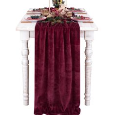 the table is set with plates and napkins on it, along with a red velvet runner