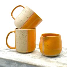 three orange and white cups sitting on top of a table